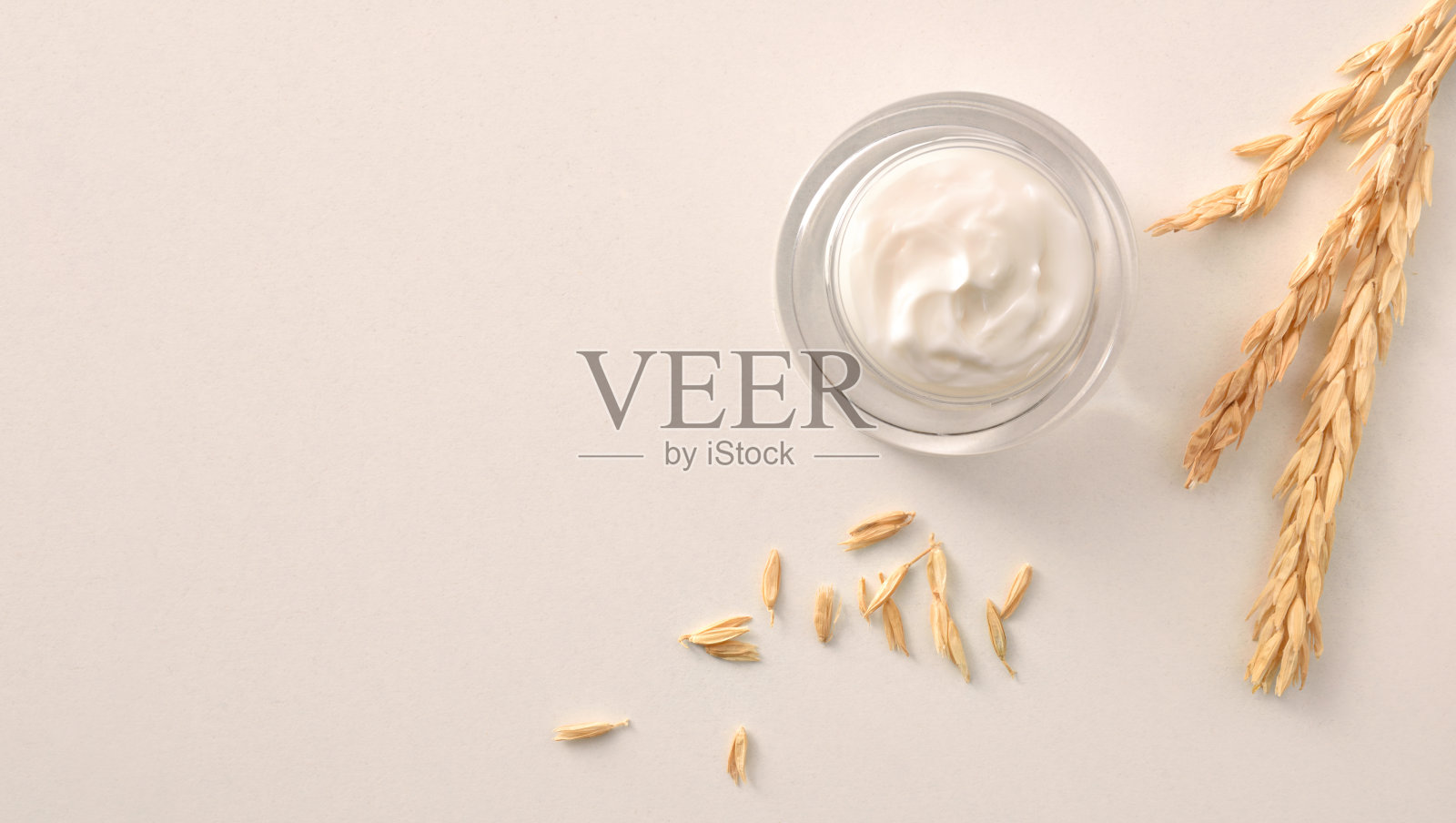 燕麦保湿霜在玻璃罐与尖刺白色背景照片摄影图片