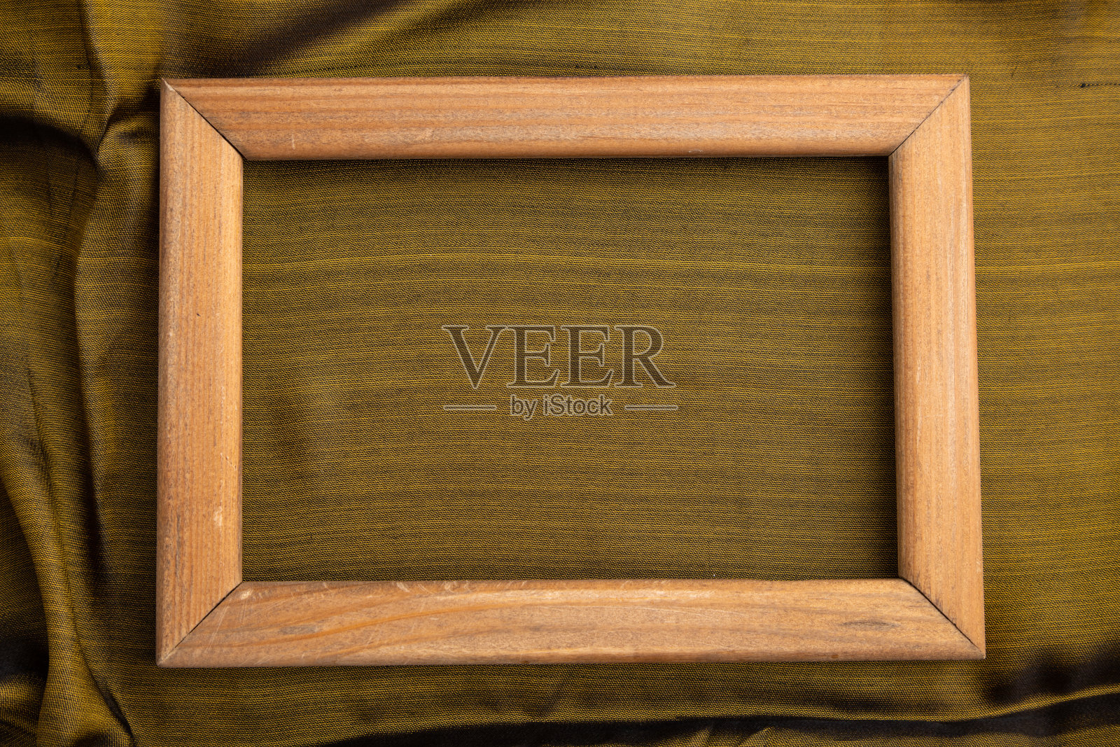 木制框架上光滑的橄榄色和金色的丝绸组织。俯视图，平铺，自然纺织背景和纹理。照片摄影图片