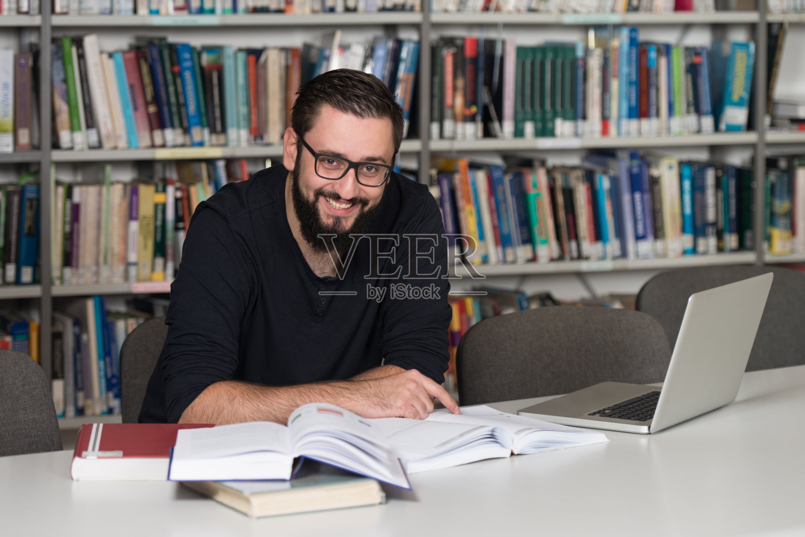 快乐的男学生在图书馆用笔记本电脑照片摄影图片