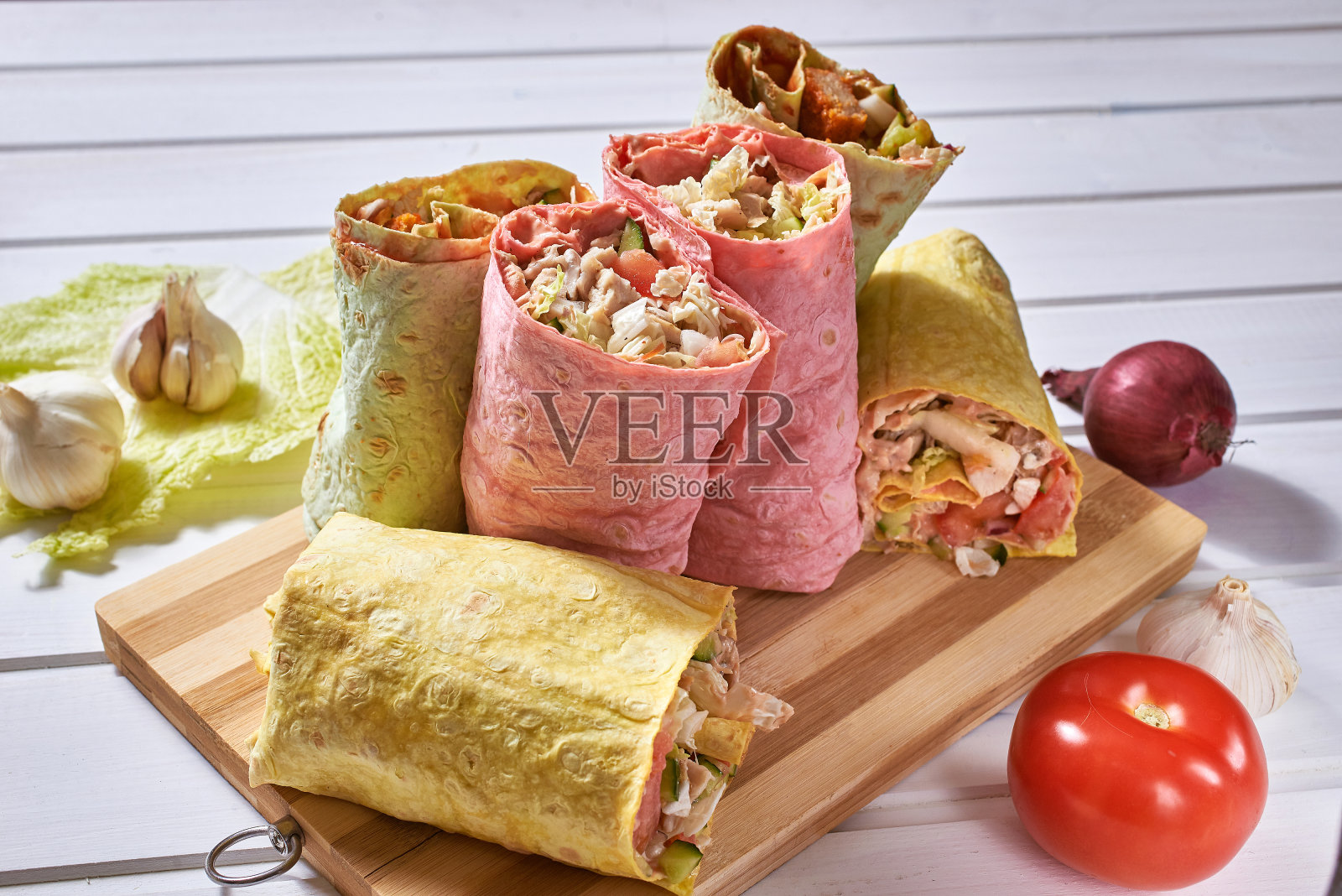 几种类型的卷在彩色皮塔饼在白色的木制背景。前视图。照片摄影图片