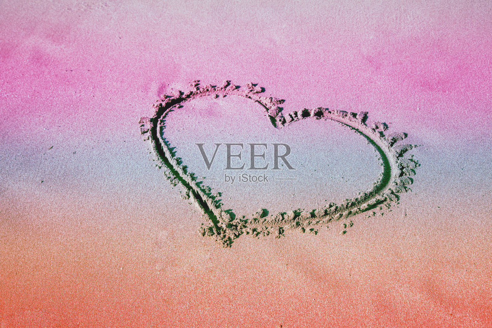 沙滩上刻有心形铭文。渐变的颜色照片摄影图片