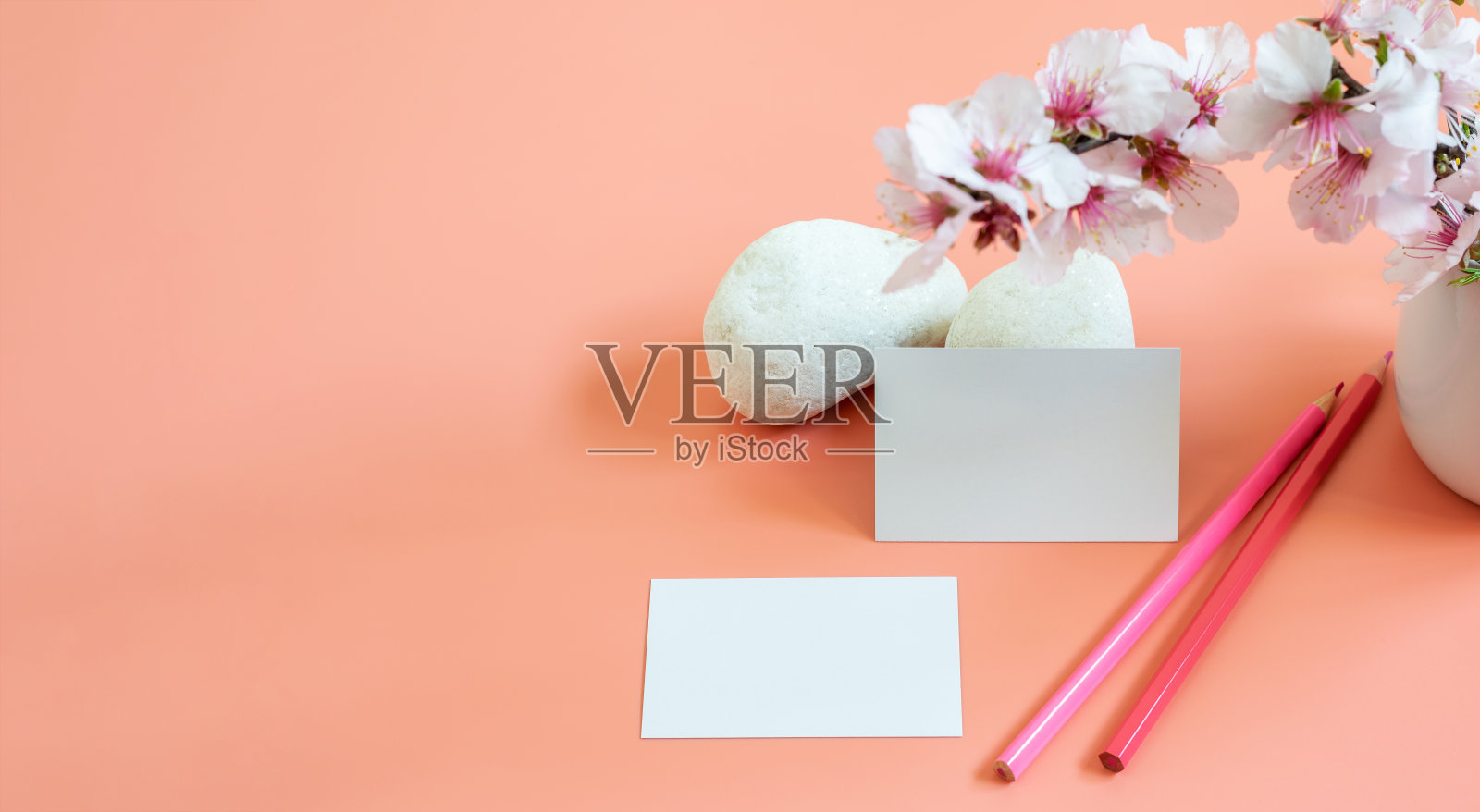 模型模板的名片空白，铅笔和天然杏仁枝在粉红色的背景。美丽的杏花和白色的石头。横幅照片，文字或标志或任何信息的空间。照片摄影图片