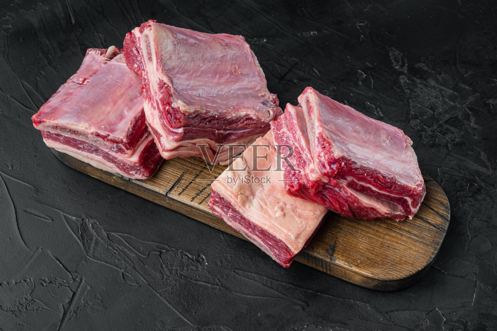 生牛排骨，黑石背景照片摄影图片