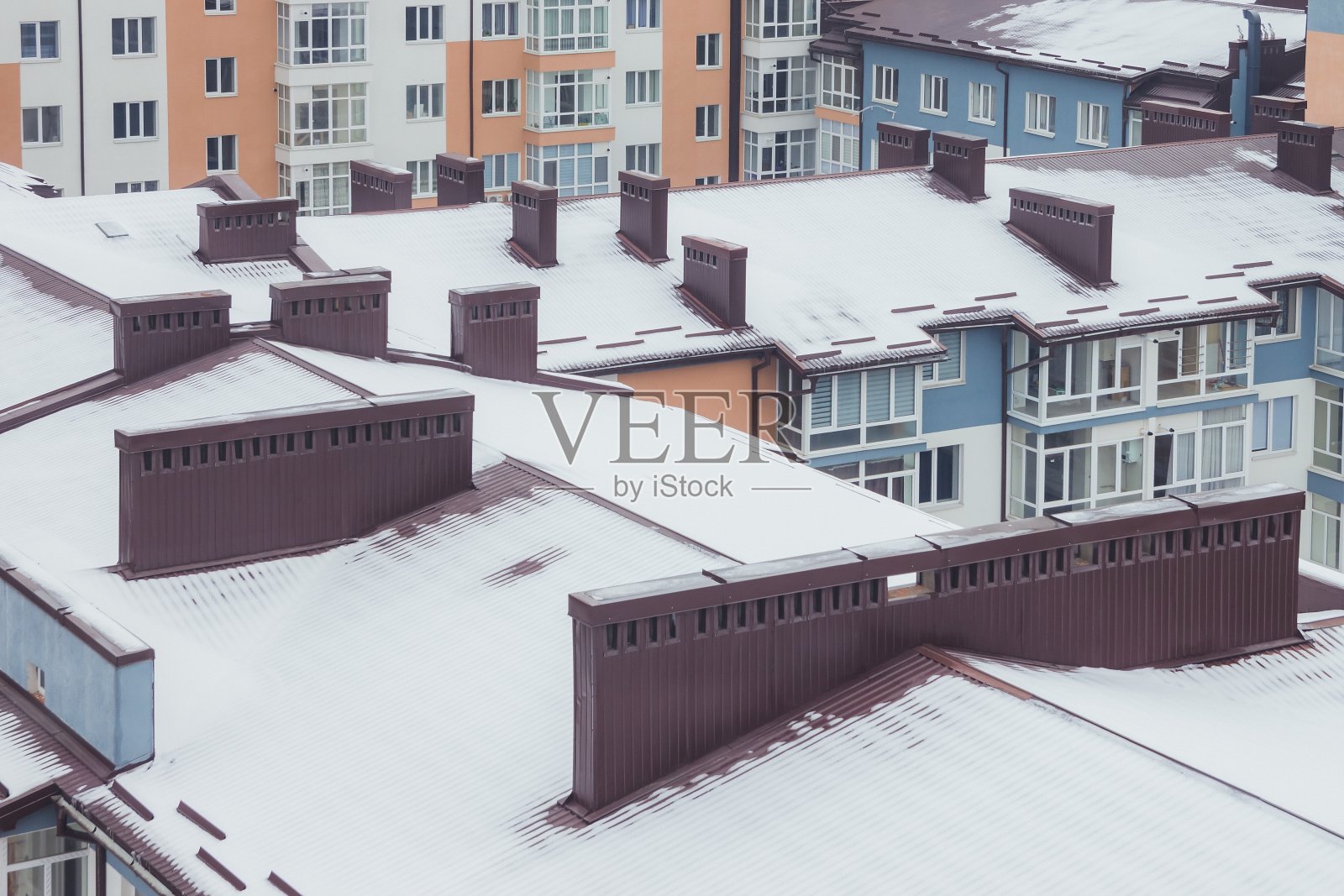 有烟囱的屋顶在冬天被雪覆盖。冬天大城市里有高大的房子照片摄影图片