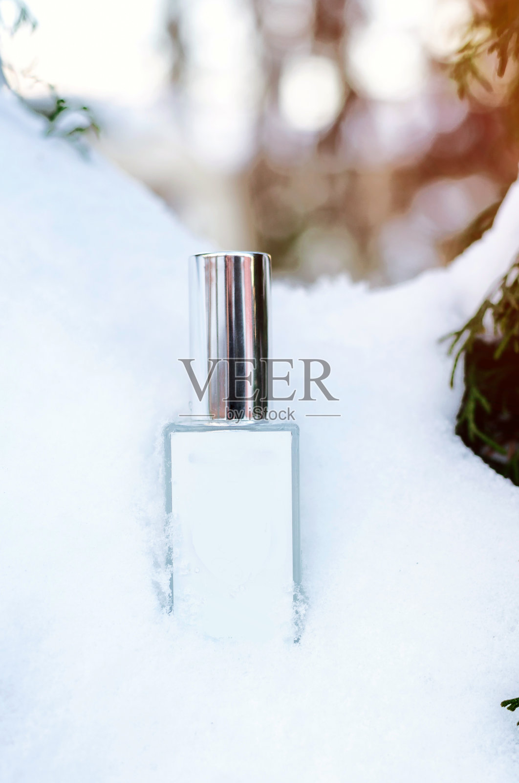 在雪地里，放着一瓶有拷贝空间的香水。太阳射线。冬季的寒冷和抗冻概念。模拟。照片摄影图片