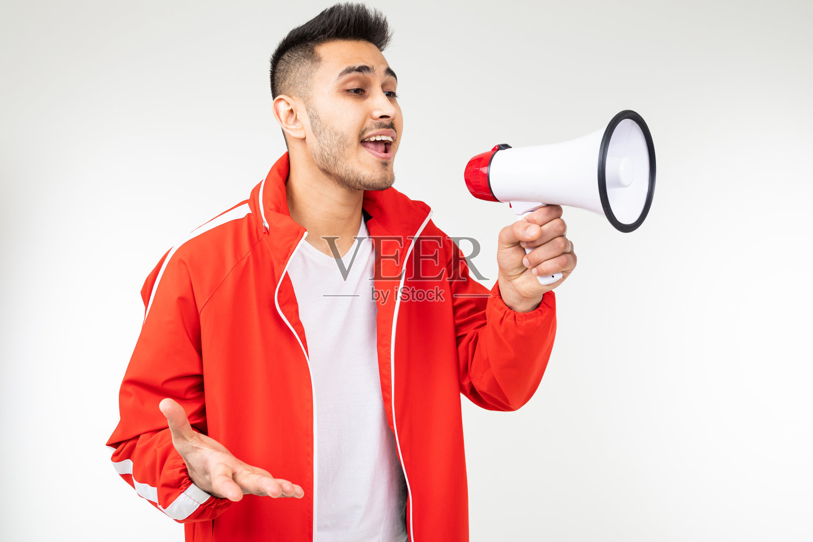 一个迷人的男人，手里拿着扩音器，在白色的背景下高喊着购物打折的消息照片摄影图片