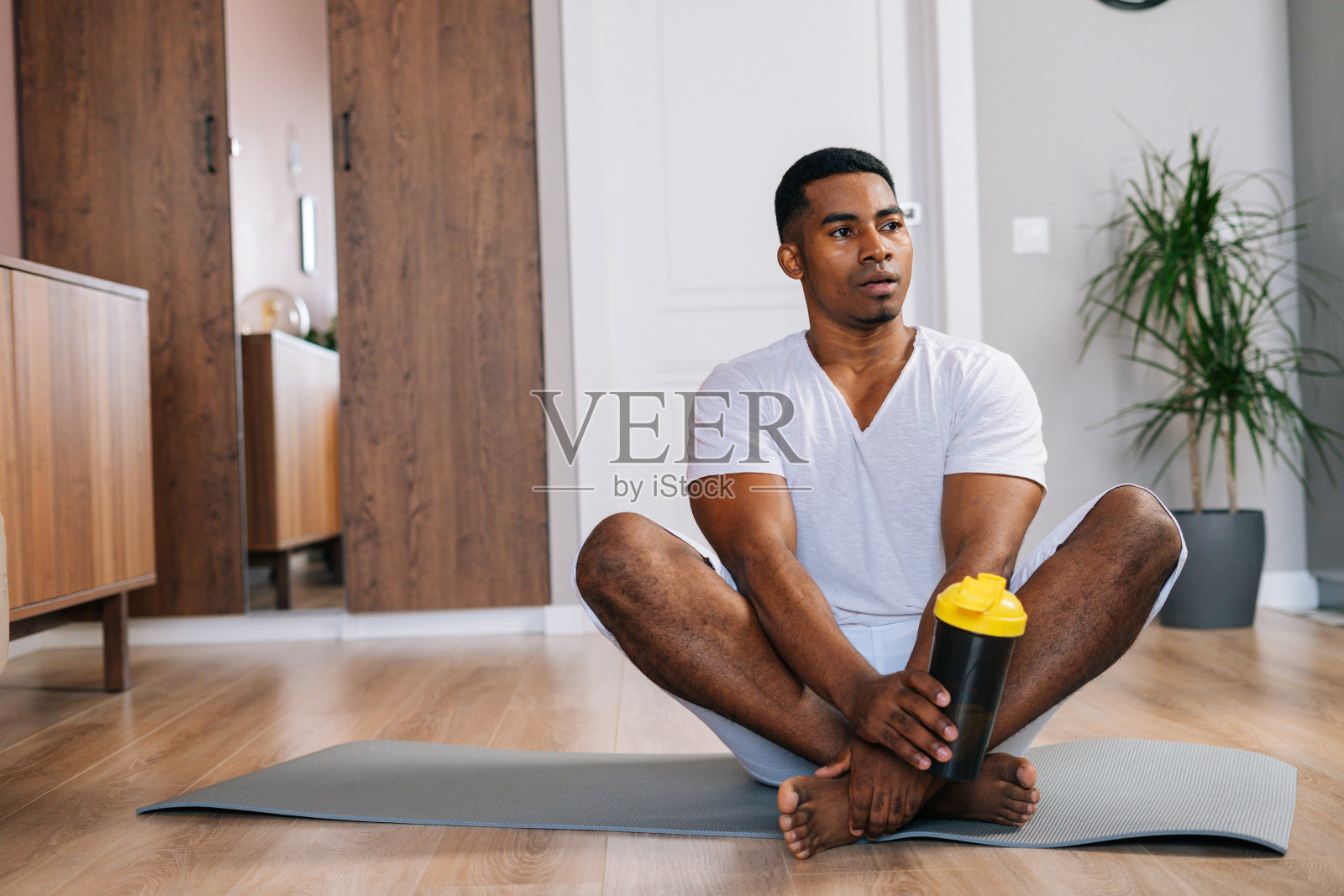 非裔美国人，运动后盘腿坐在运动垫上，喝着水照片摄影图片