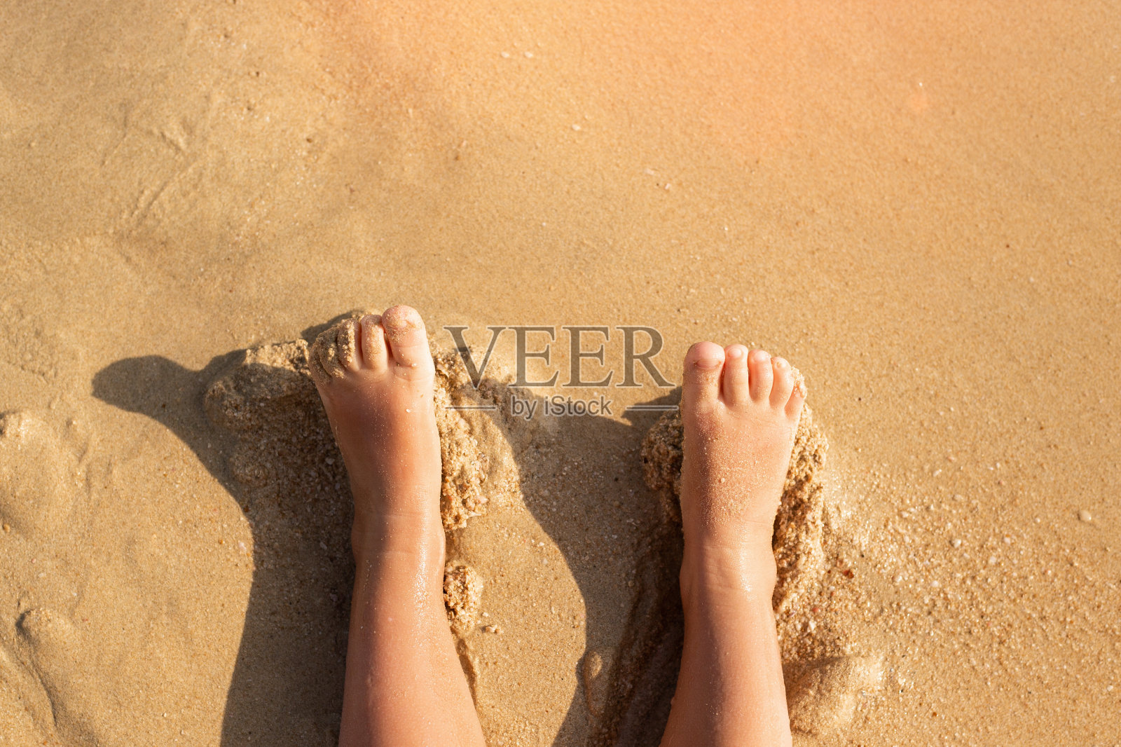 宝宝的两只脚躺在沙滩上，在沙滩上。旅游、度假。照片摄影图片