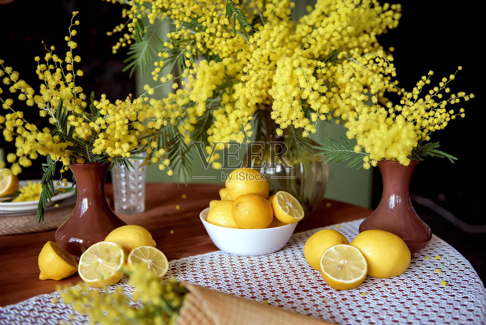 花瓶里插着黄花，桌上摆着一盘柠檬照片摄影图片