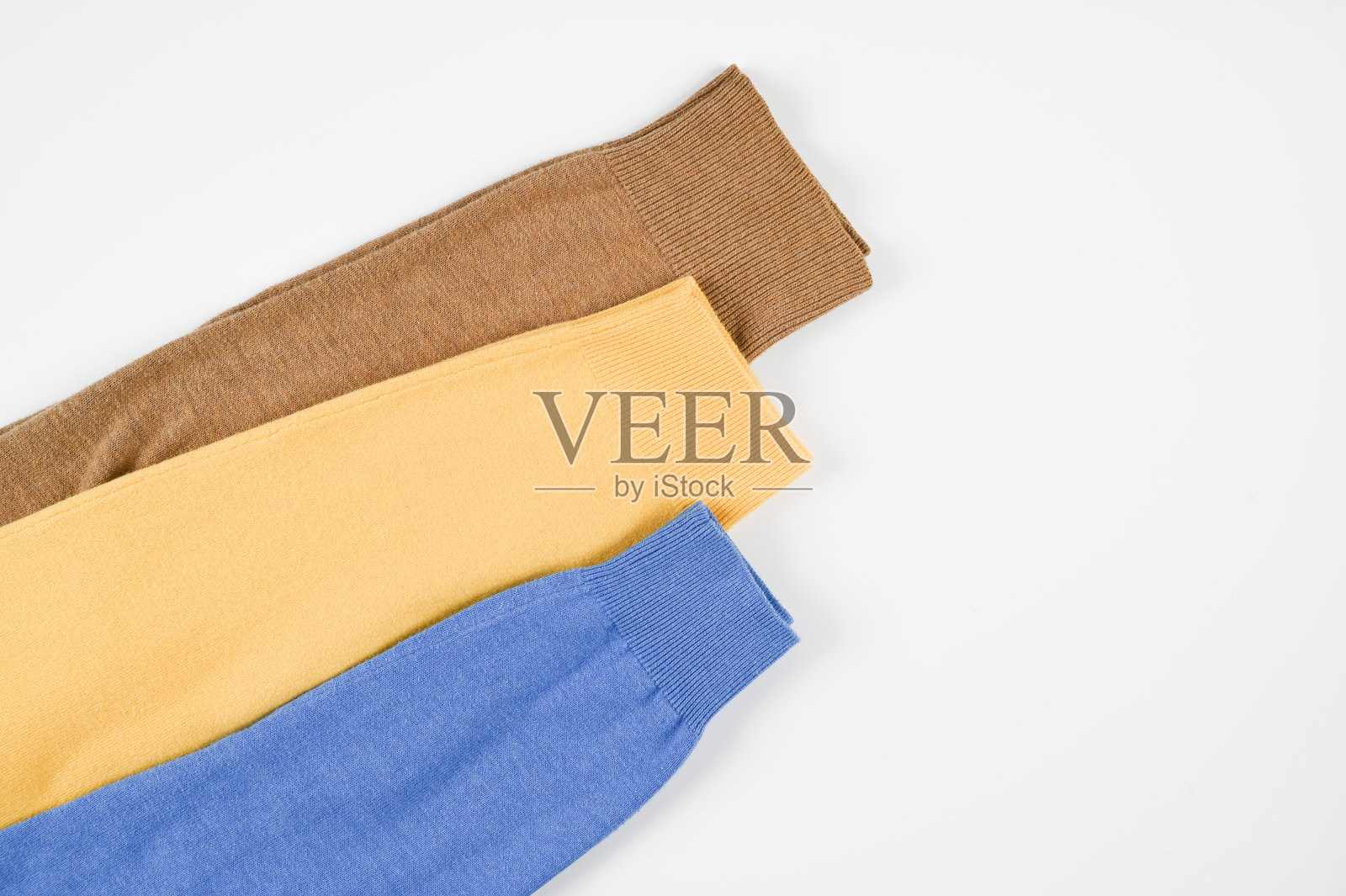 三种温暖不同的针织羊毛衫的袖子棕色，黄色和蓝色孤立在白色上。温暖的布料，不同的颜色，时髦的春天或秋天的外观照片摄影图片