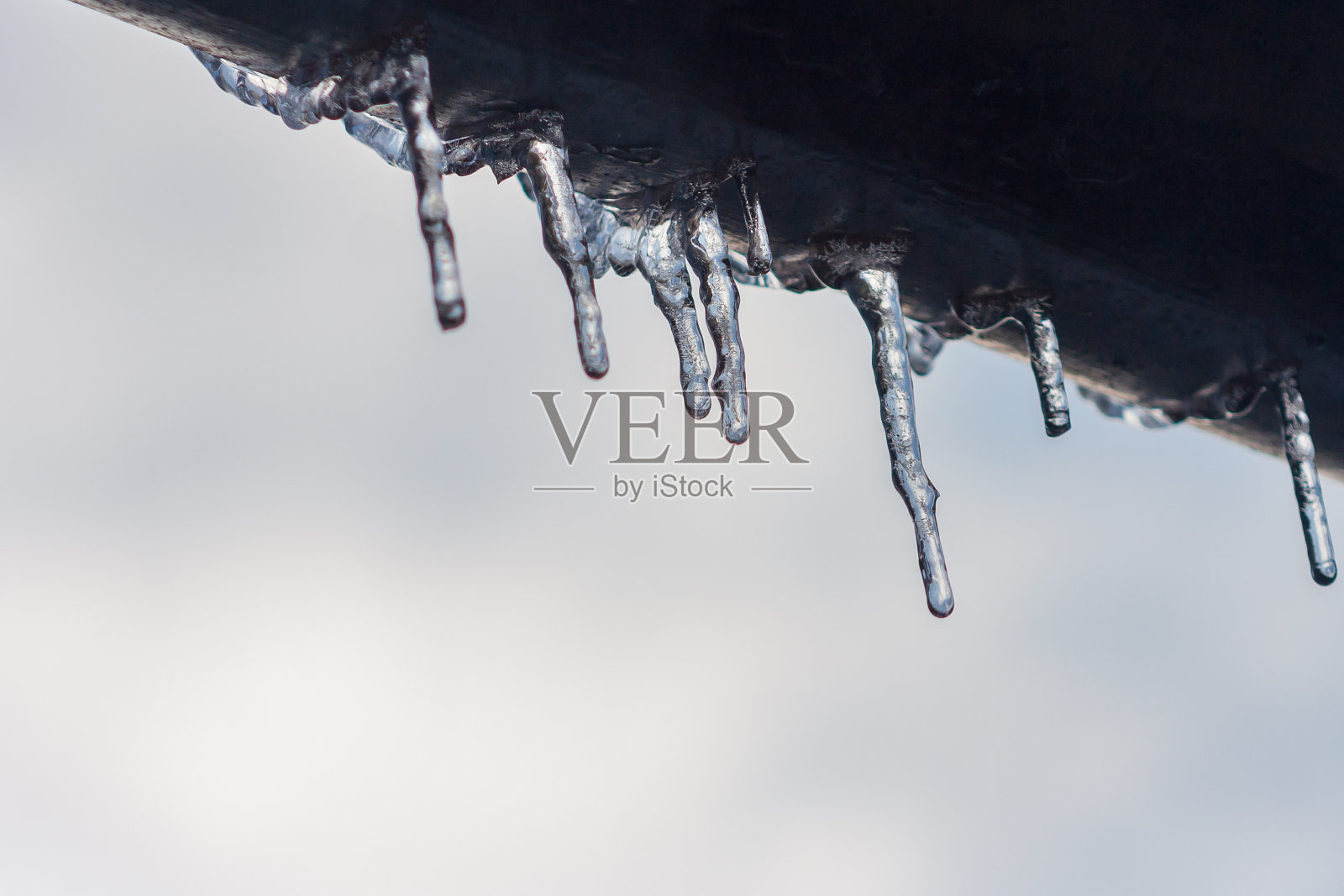 屋顶上挂着冰柱。冬天的概念。特写镜头危险冰柱。冰冻气候模式。霜冬天照片摄影图片