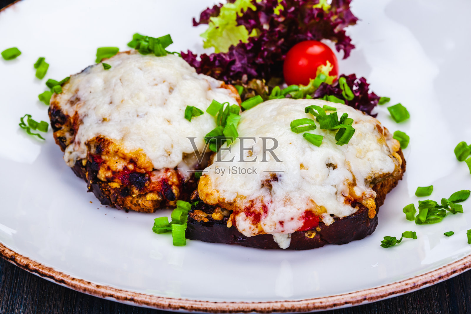 健康的吐司，烤黑麦面包，蕃茄，融化的奶酪，白盘子。照片摄影图片