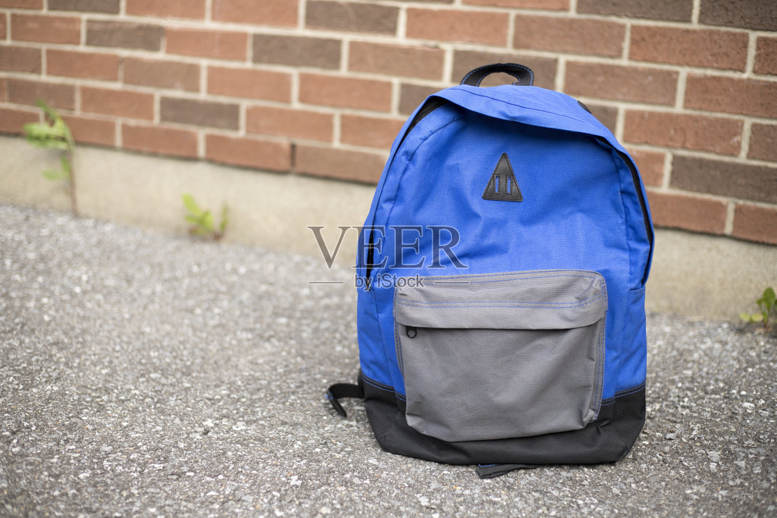 蓝色书包在红砖学校的路上。照片摄影图片