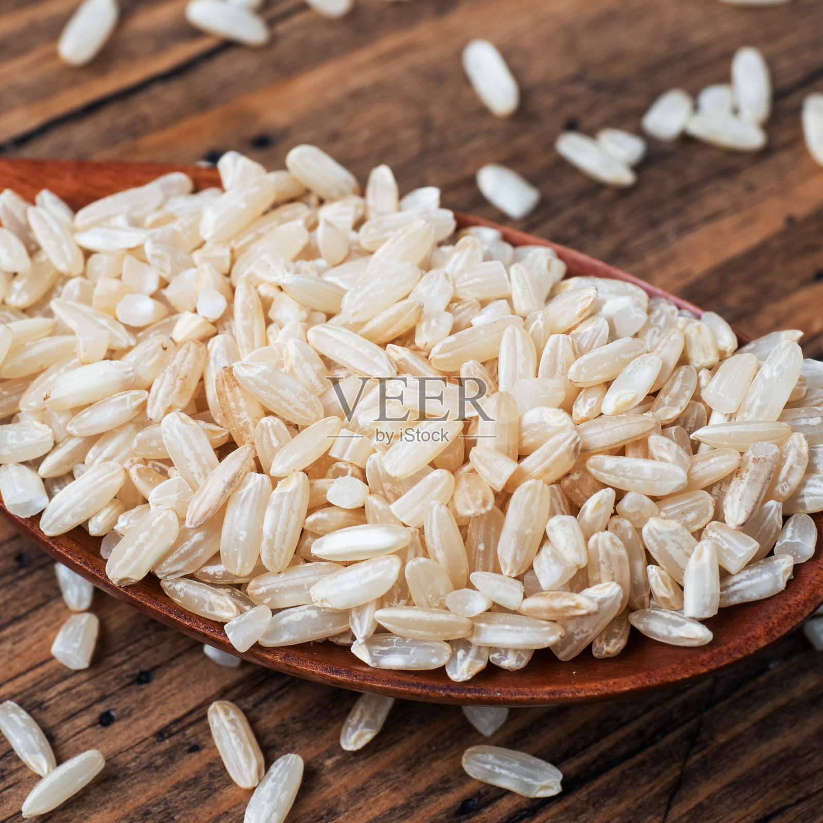 糙米生长粒放在勺子里，木质背景拉近照片摄影图片