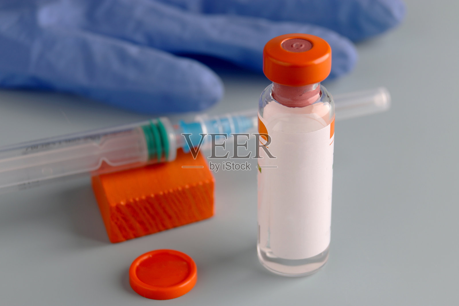 接种疫苗。医用手套，一个带疫苗的玻璃瓶和一个注射器，放在浅色背景上。制药行业。医疗和免疫。照片摄影图片