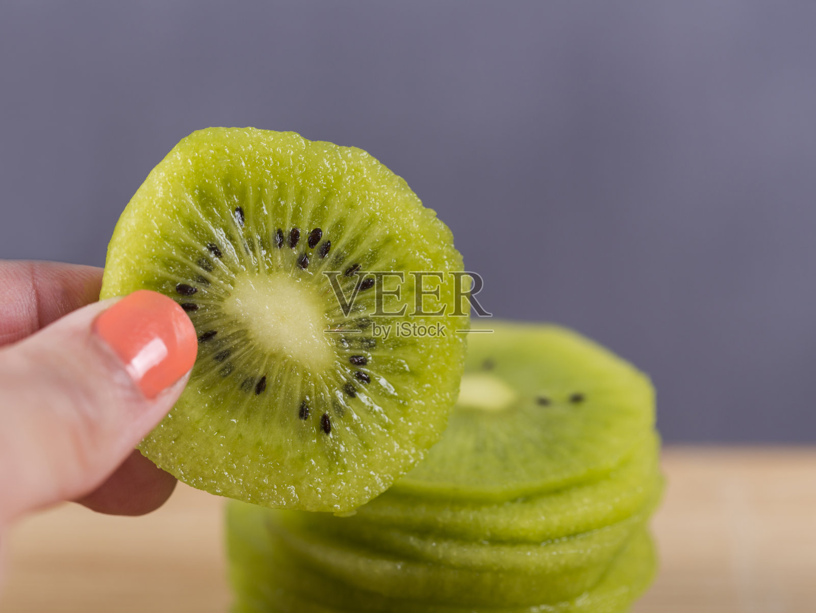 用一片猕猴桃拉近女人的手。照片摄影图片