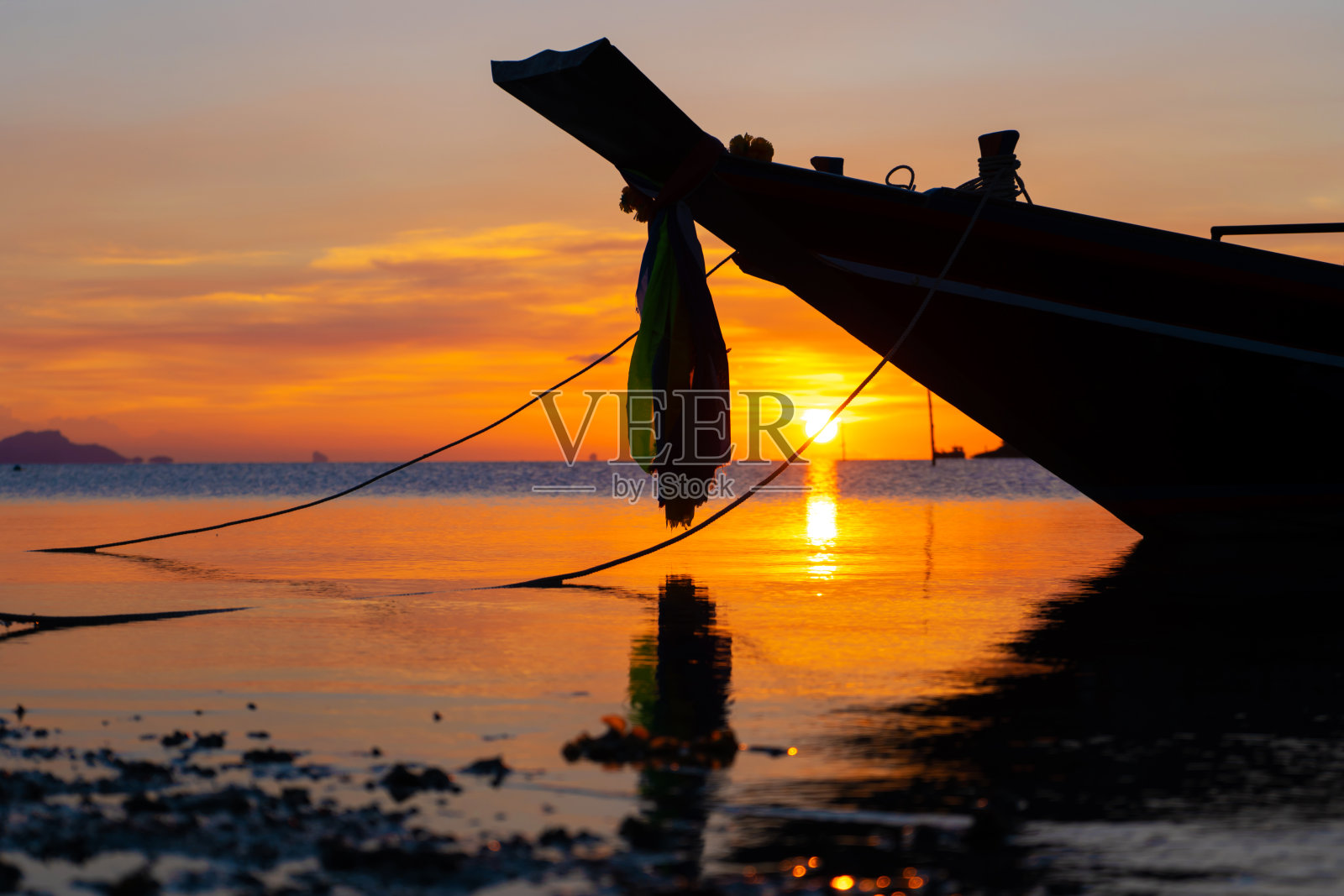 美丽的日落在泰国的一个热带岛屿的海岸，一艘船的剪影在海洋照片摄影图片