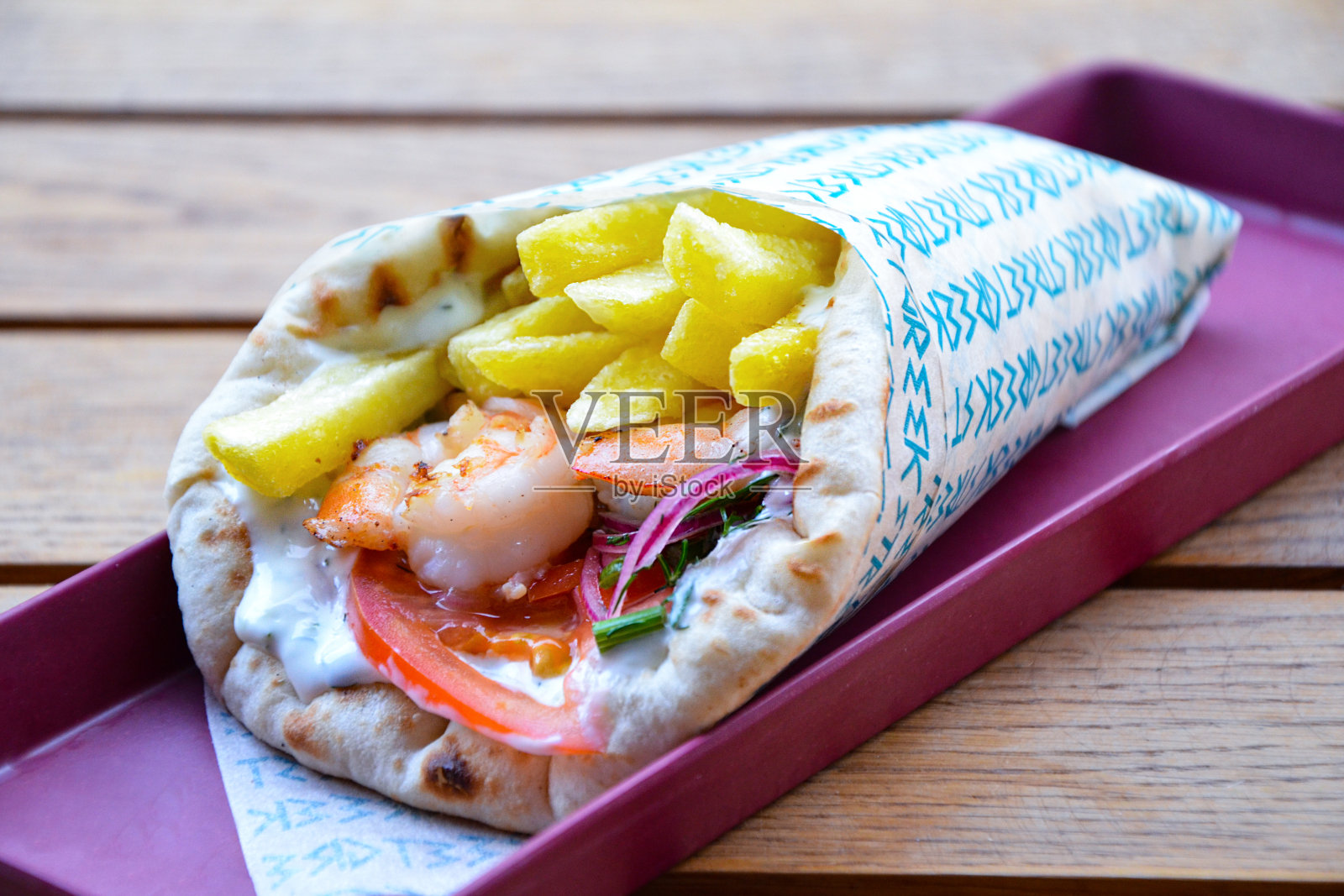 特写的传统希腊小吃陀螺与虾在街头咖啡馆的木桌上。照片摄影图片