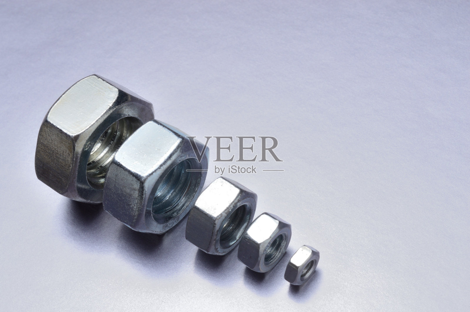 5个新的从大到小不同尺寸的铬螺母排列在一起。金属的背景。特写镜头。照片摄影图片