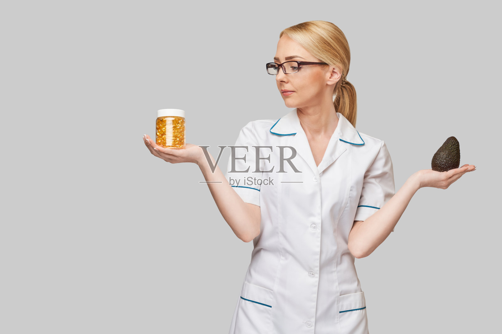 保健和饮食概念-医生营养学家或心脏病学家持有胶囊鱼油维生素D和omega-3脂肪酸和鳄梨照片摄影图片