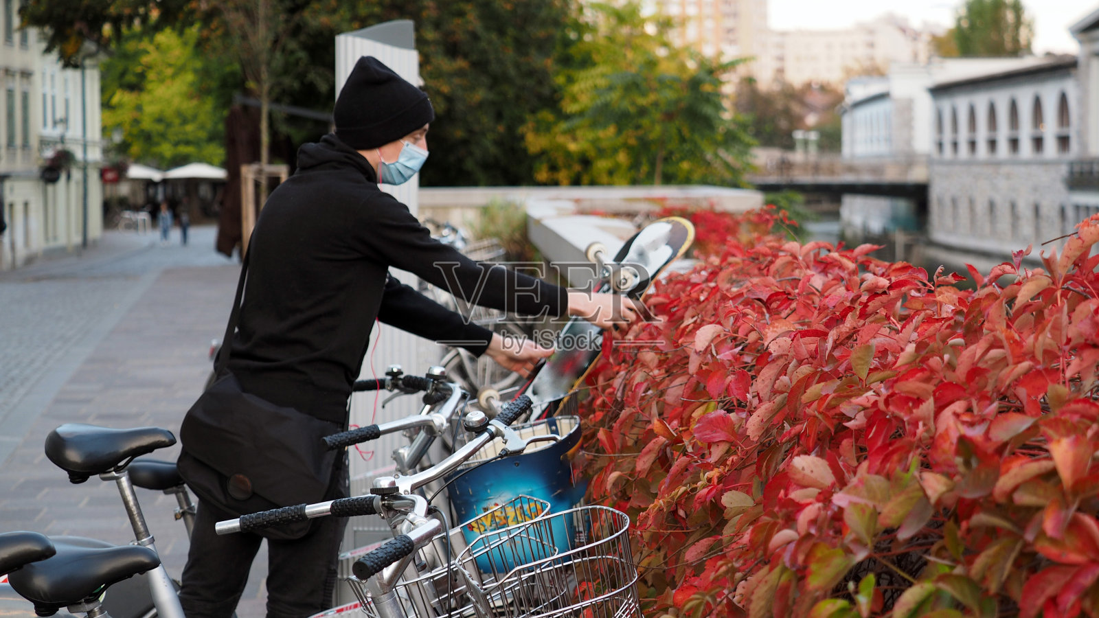 年轻的滑板手用他的智能手机在城市里租共享单车照片摄影图片