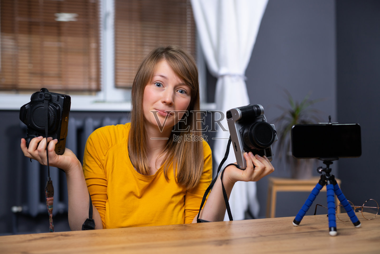 有影响力的人拿着两台相机。视频博主，讲述她使用智能手机摄像头的经历。内容创作者社交媒体新媒体明星，专业的在线视频拍摄设备照片摄影图片
