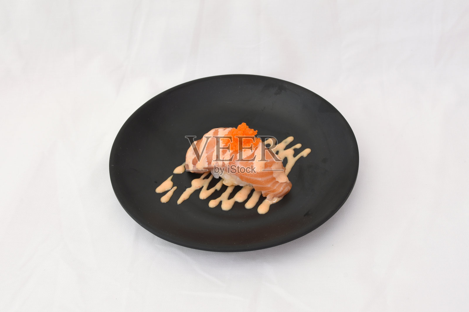 生三文鱼寿司配上虾子和蛋黄酱放在黑色的盘子上，孤立在白色的背景中照片摄影图片