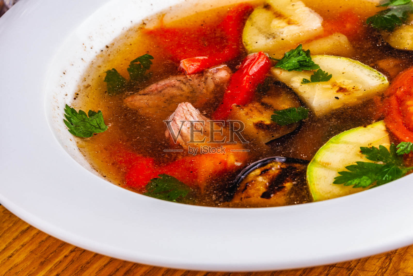 白盘子里有肉和烤蔬菜的汤照片摄影图片