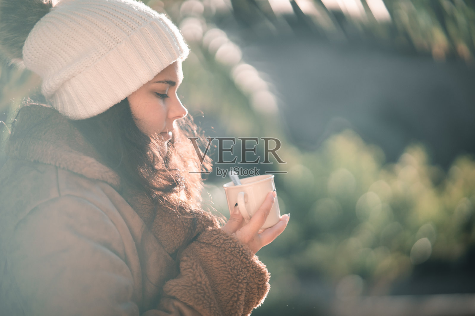 戴着羊毛帽子的女孩坐在外面照片摄影图片