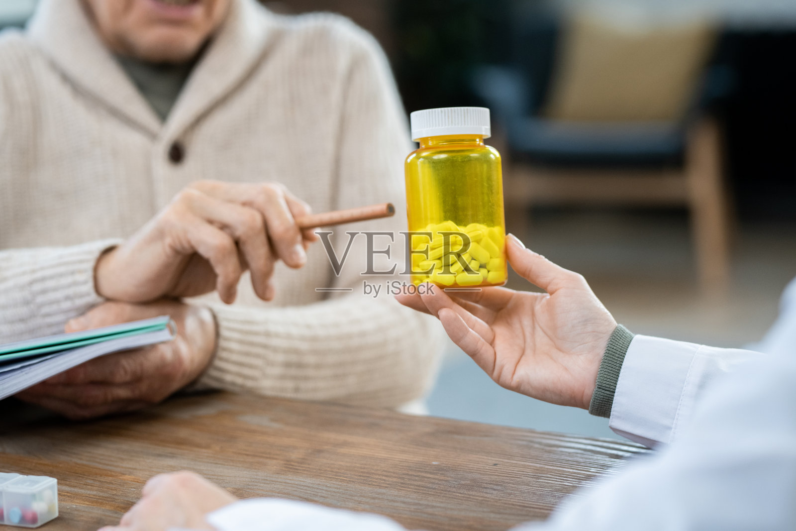 便服老人的手指着医生手中的药瓶照片摄影图片