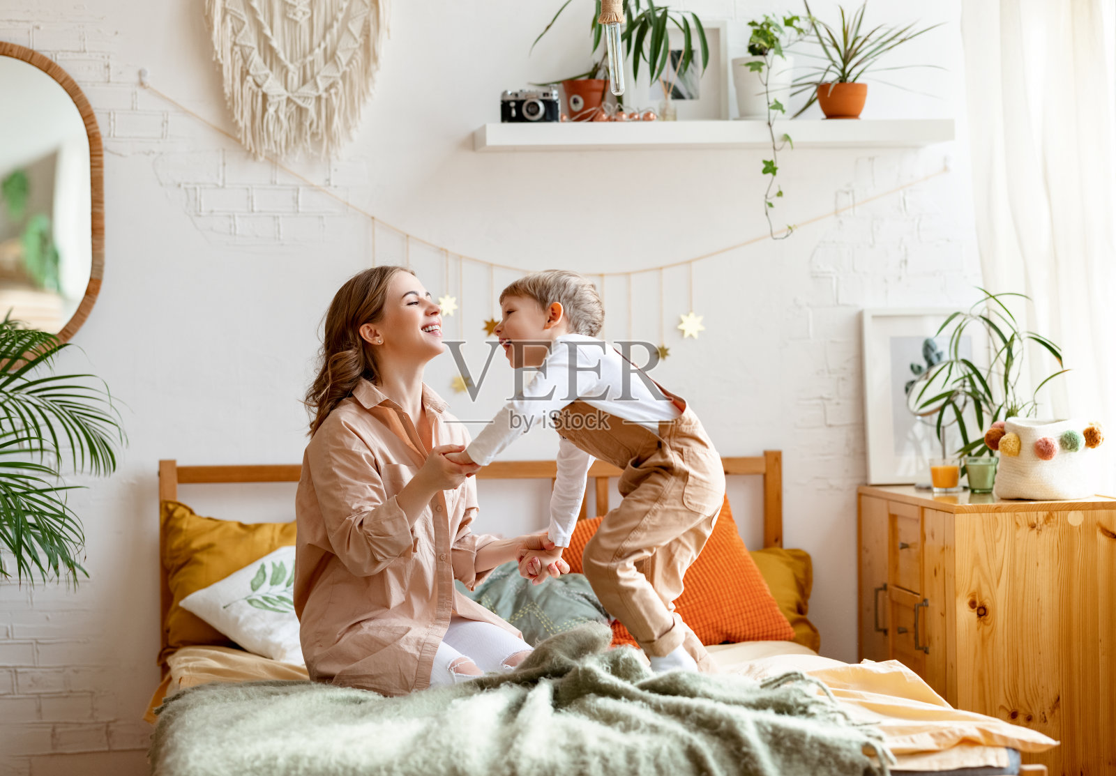 快乐的女人和男孩在卧室里玩照片摄影图片
