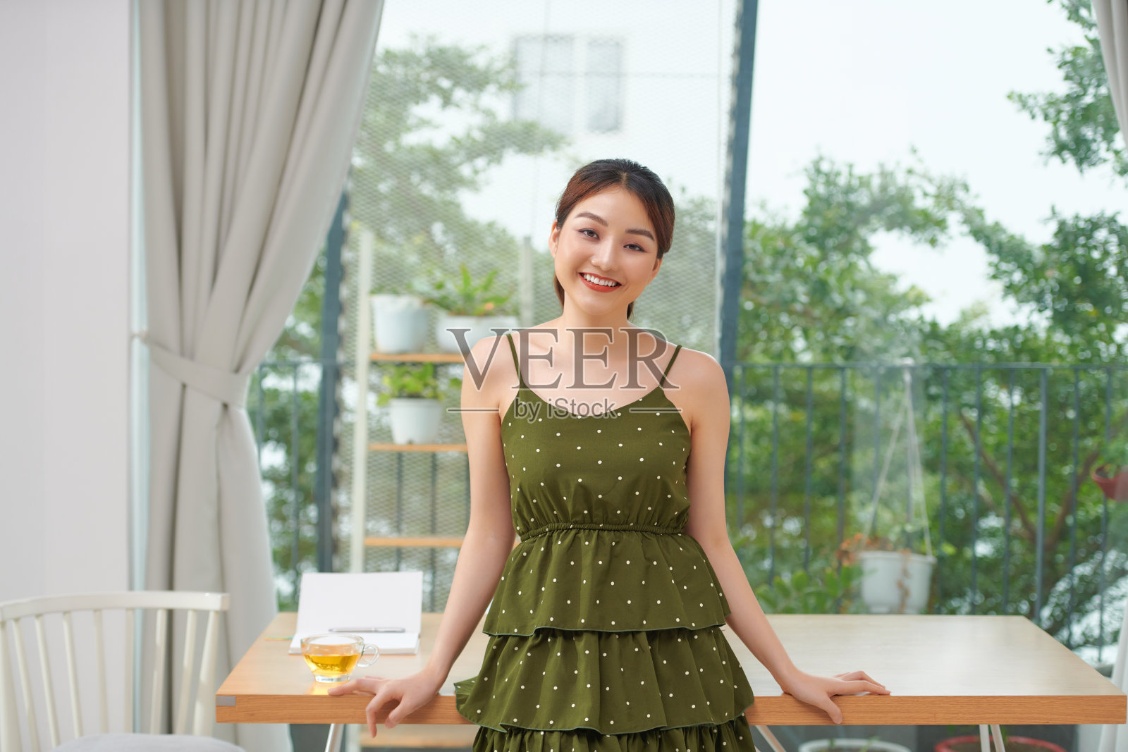 轻松微笑友好的女人坐在她客厅的桌子边缘照片摄影图片