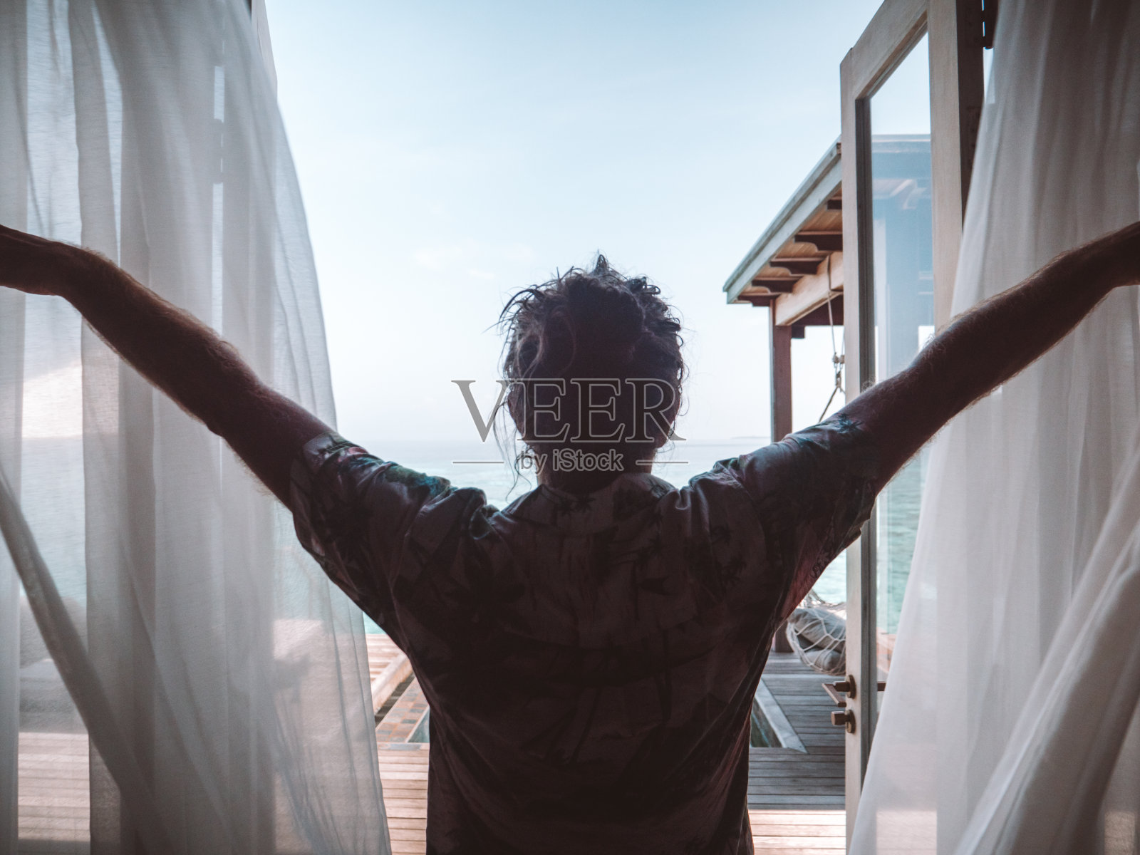 日出时分，酒店房间里的人拉开窗帘照片摄影图片