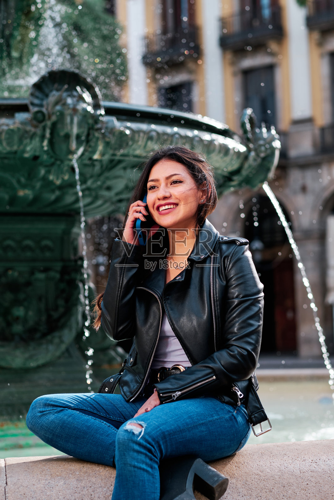 一个女人坐在外面的大街上打电话。照片摄影图片