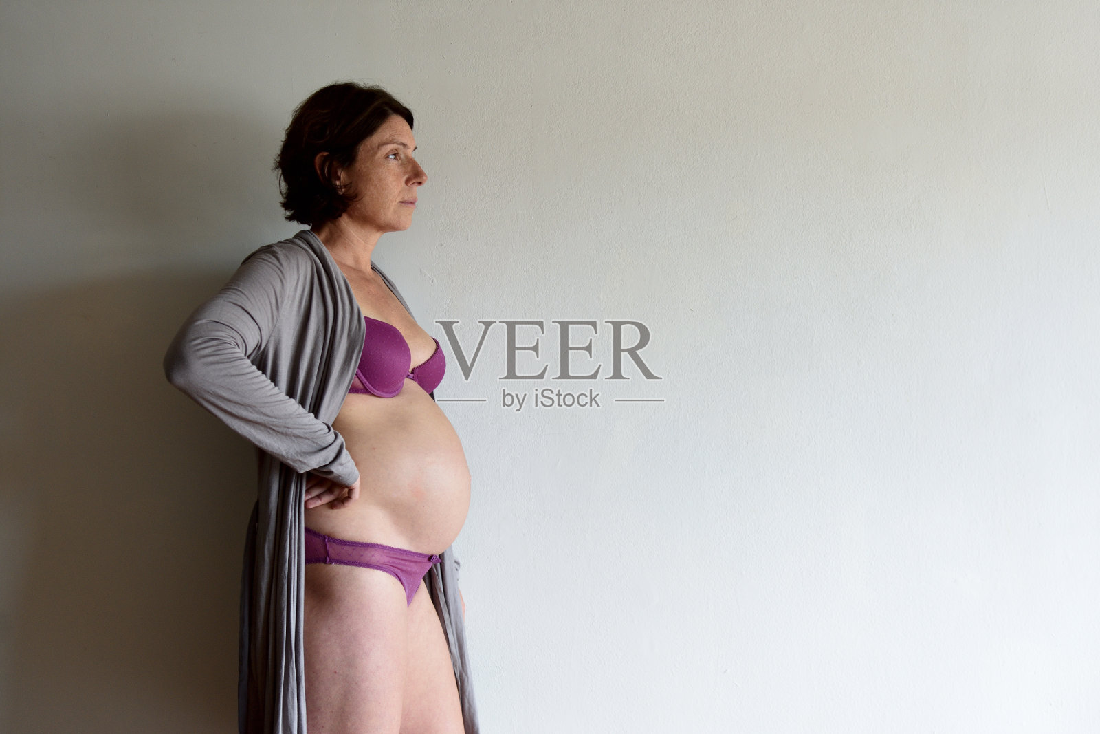 孕妇靠在墙上向一边看照片摄影图片