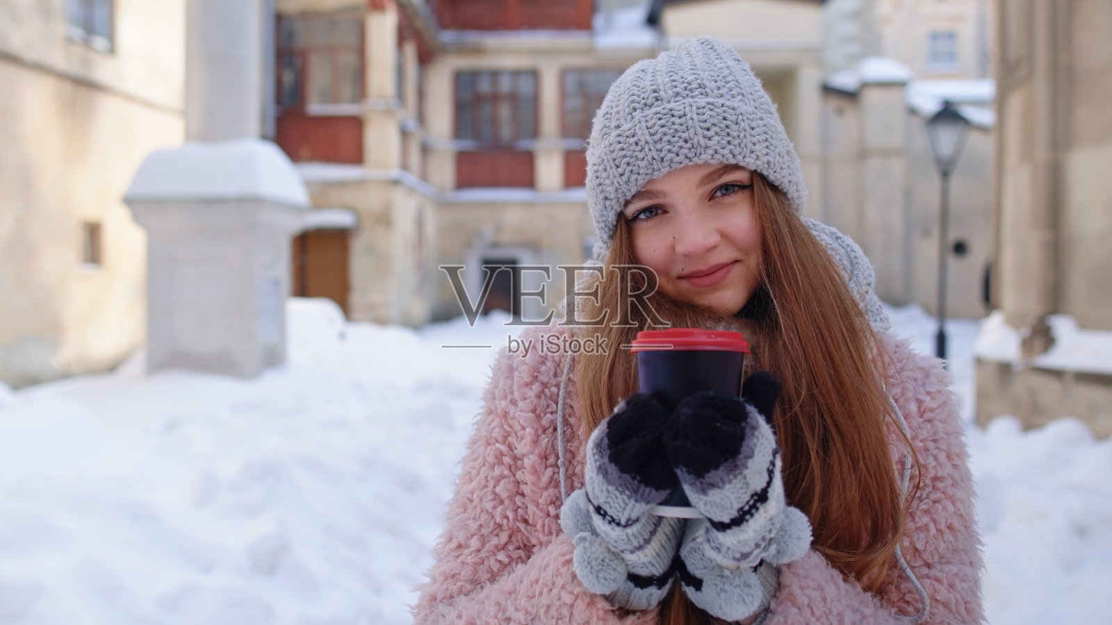 时尚的女人旅行者与热饮杯环顾城市街道在假期照片摄影图片