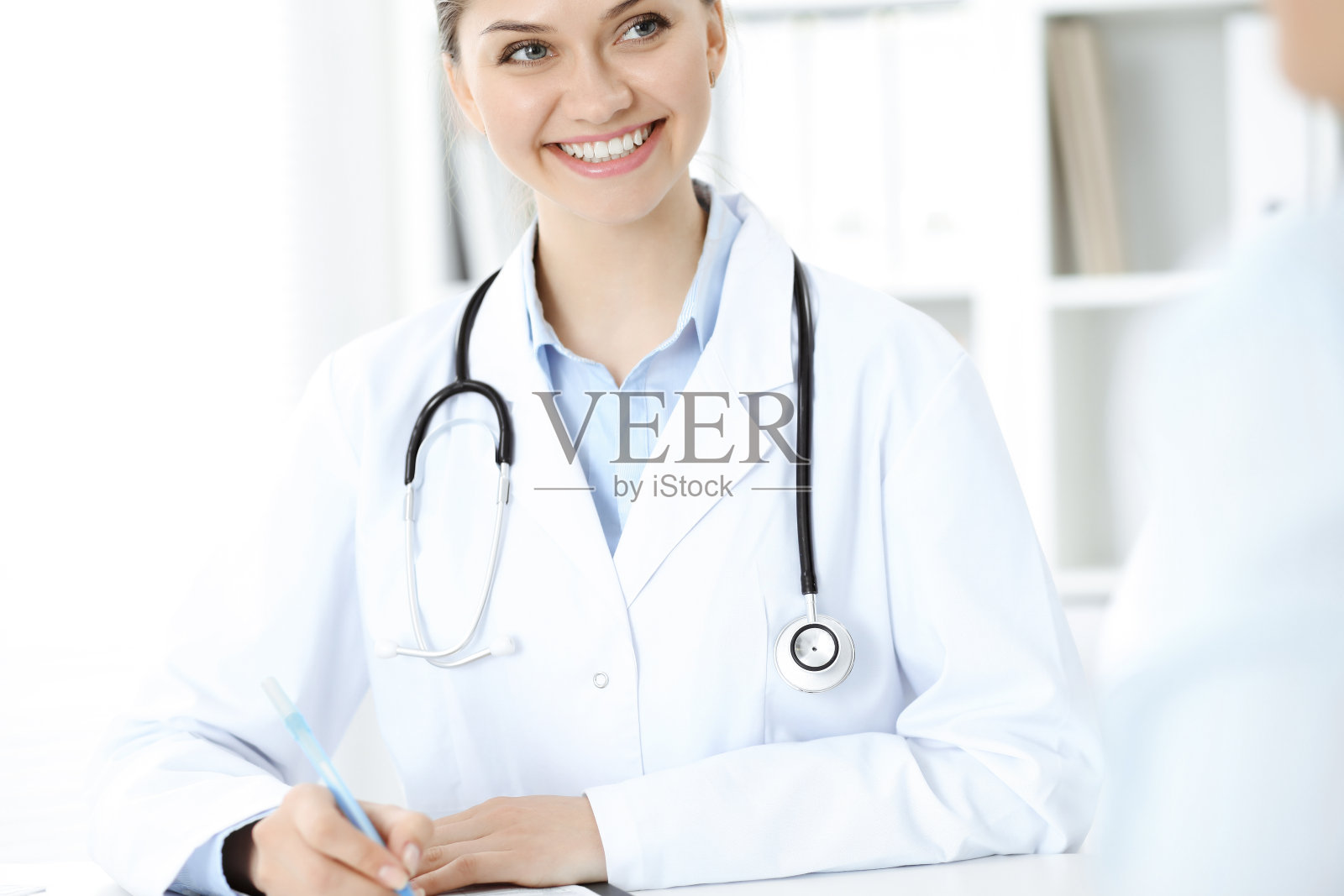 友好微笑的医生和病人坐在桌旁。非常好的消息和高水平的医疗服务理念照片摄影图片