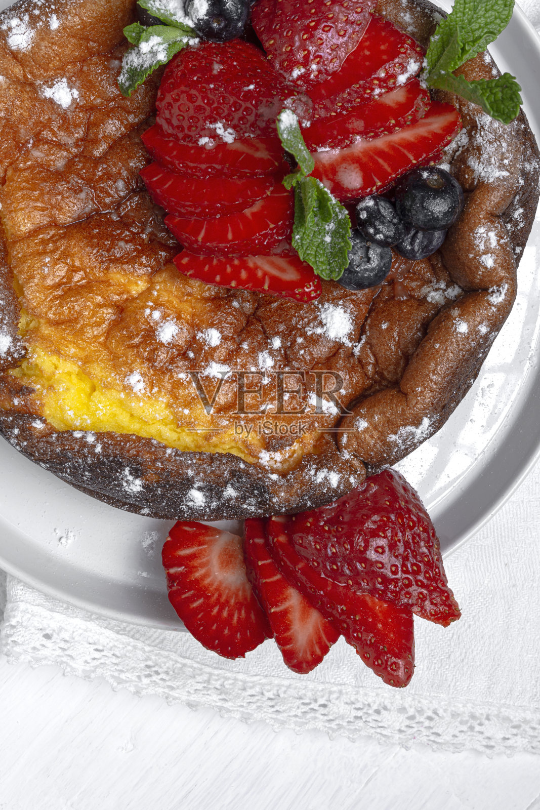 自制芝士蛋糕，上面有蓝莓、醋栗、草莓和薄荷叶。平躺照片摄影图片