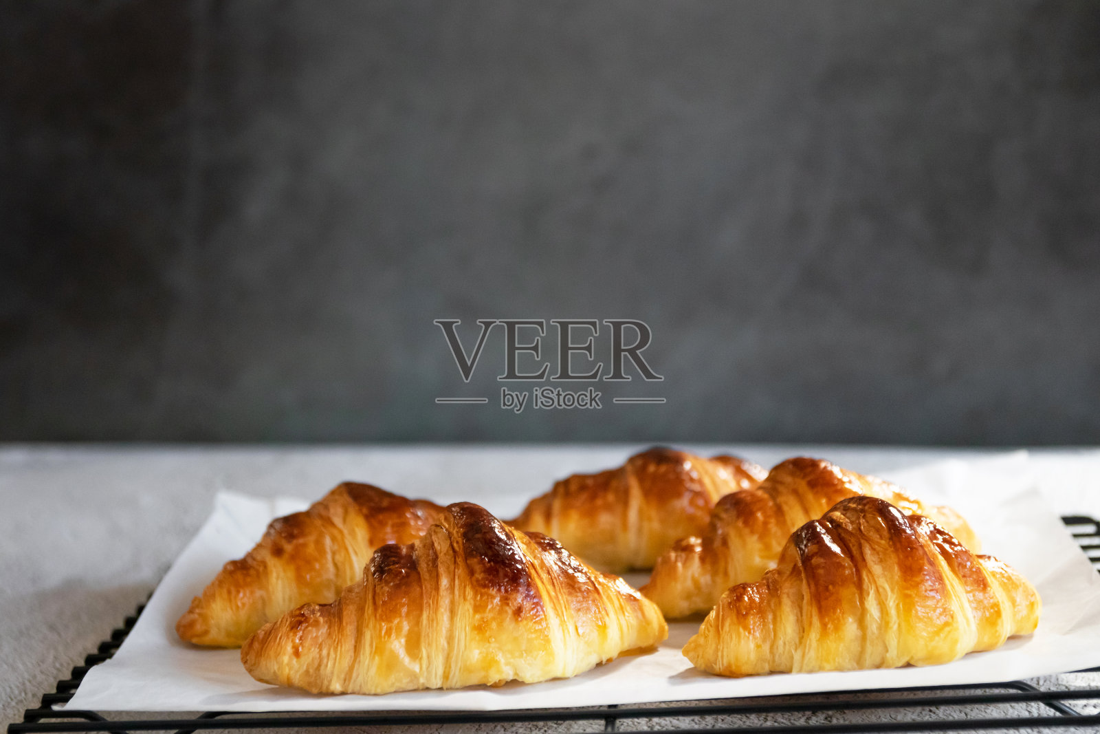 石头背景下刚出炉的新鲜牛角面包，透过窗户的自然阳光。照片摄影图片