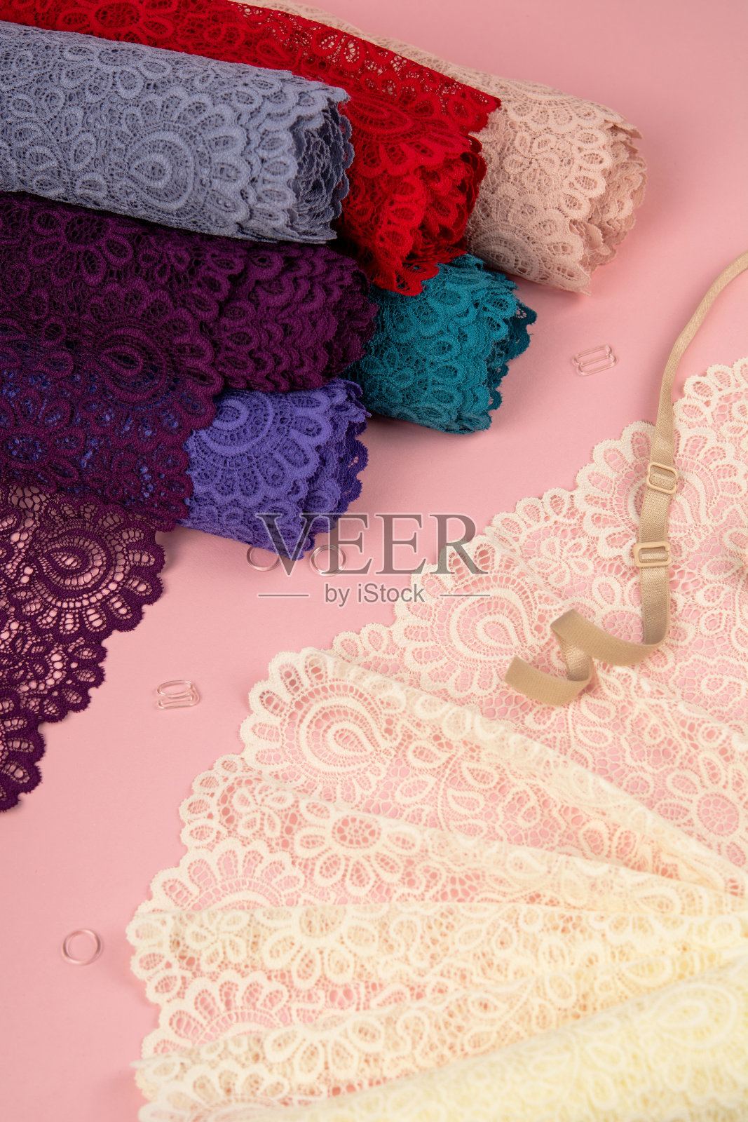 精致的蕾丝卷内裤和胸罩在粉红色的背景与塑料配件。弹性材料。用于Atelier和布料商店。照片摄影图片