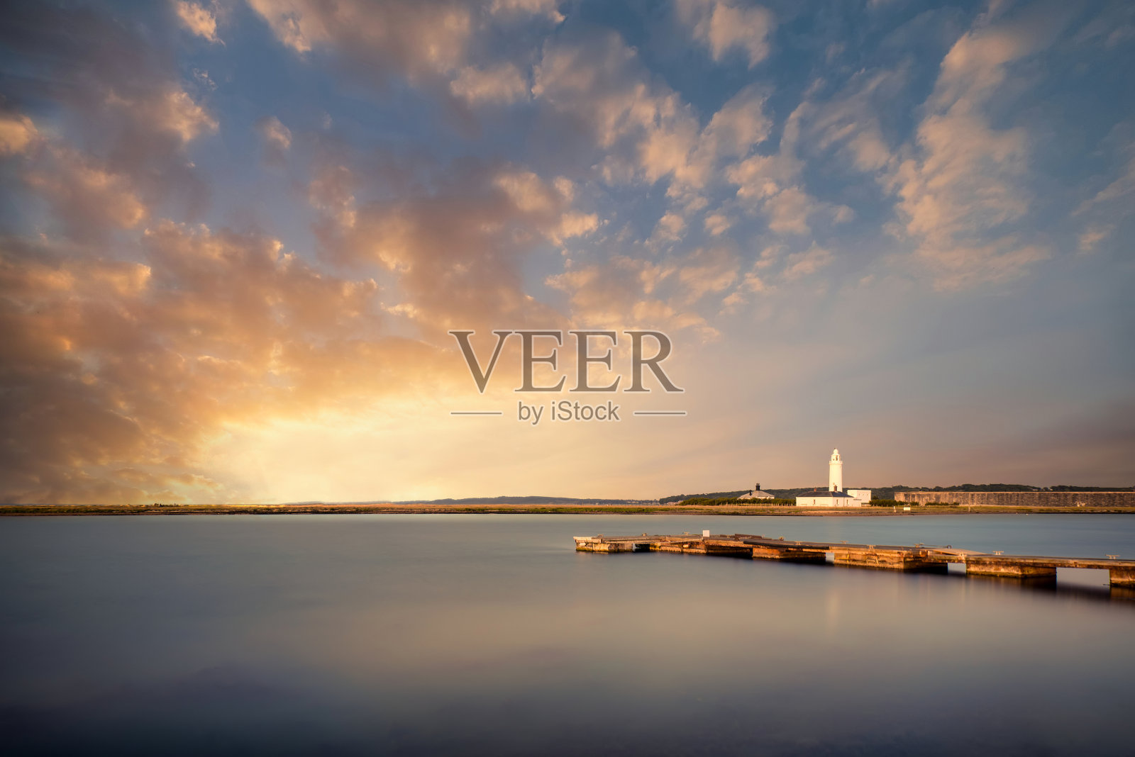 夏季日落时长时间曝光的灯塔和码头照片摄影图片