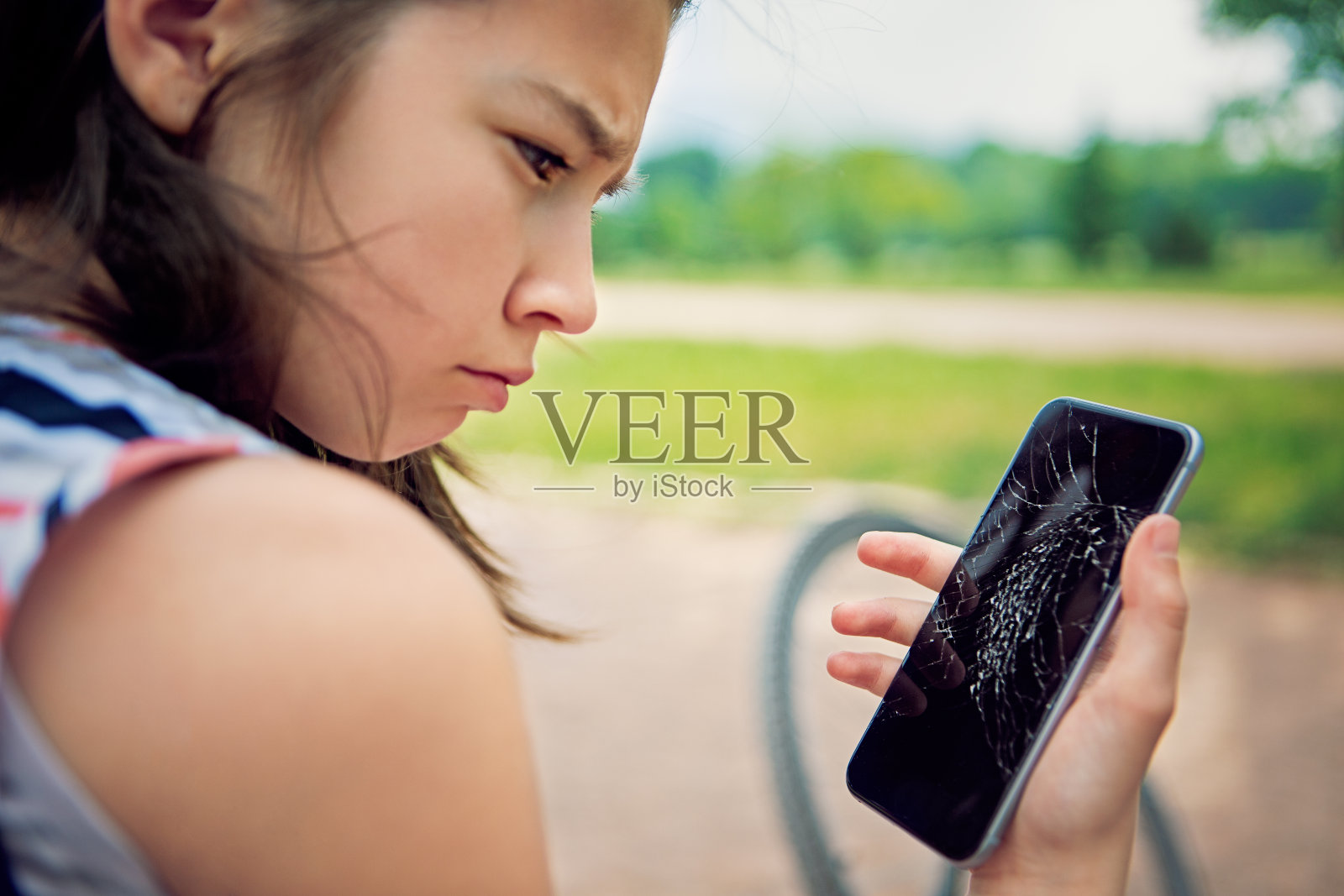 哭泣的女孩看着她坏掉的手机照片摄影图片