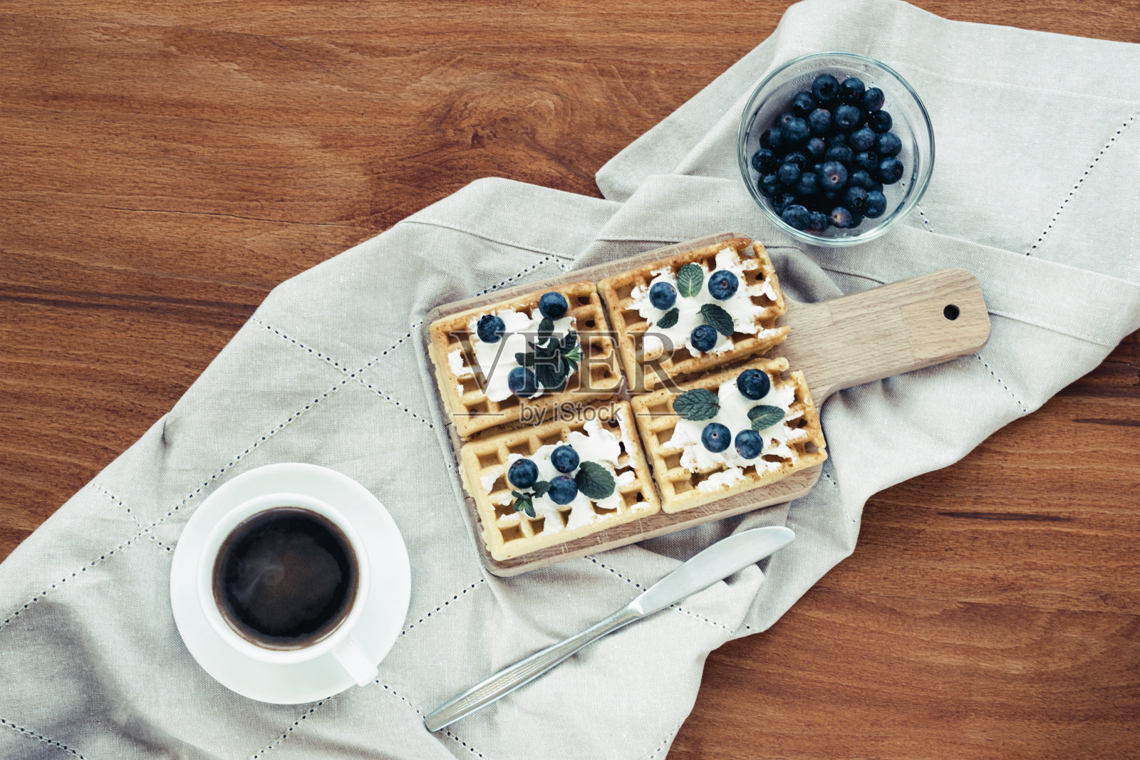 奶油和蓝莓华夫饼，桌布上放着一杯咖啡。俯视图照片摄影图片