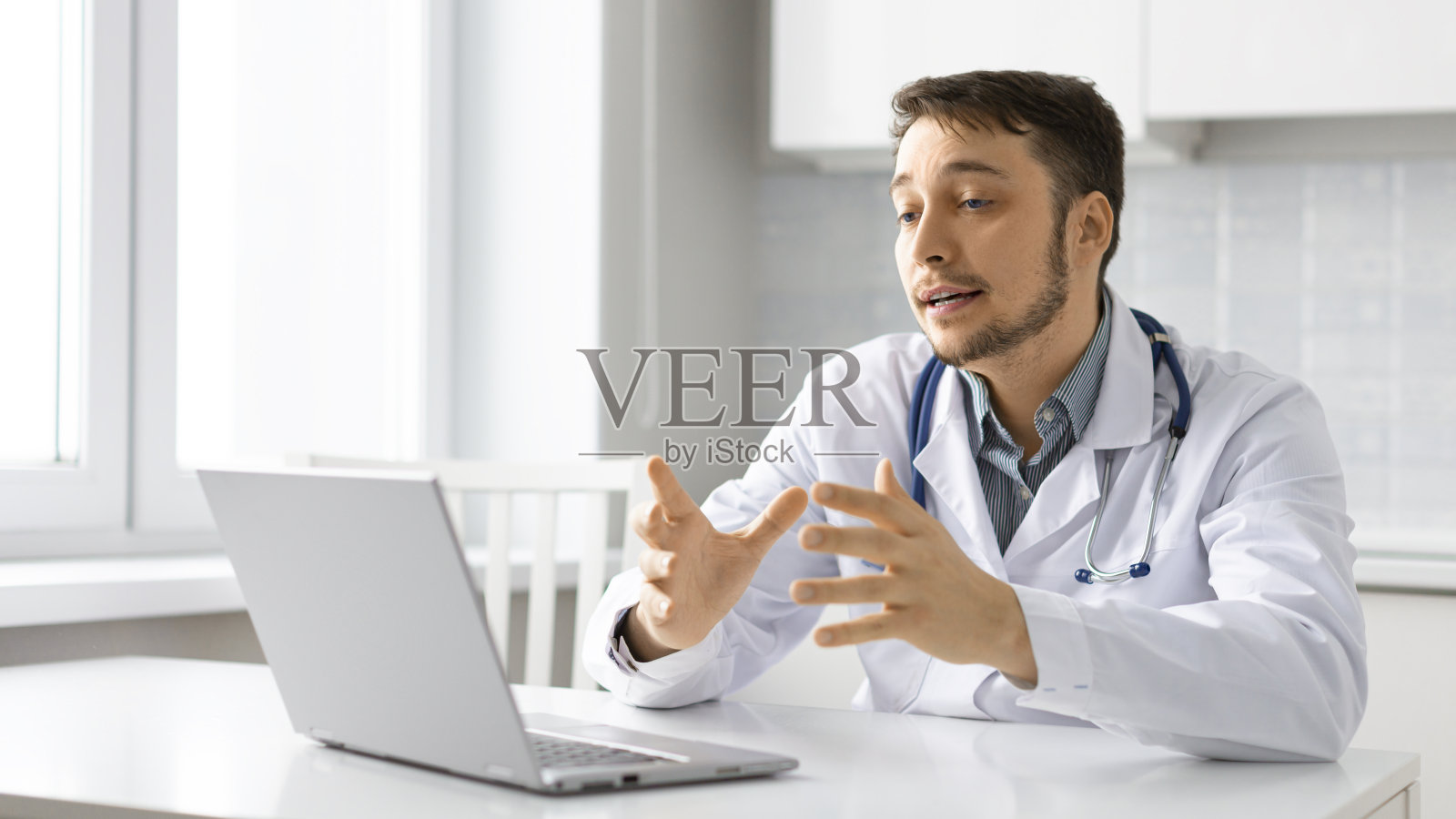 医生在笔记本电脑显示器前的照片。他为客户提供视频通信方面的建议照片摄影图片