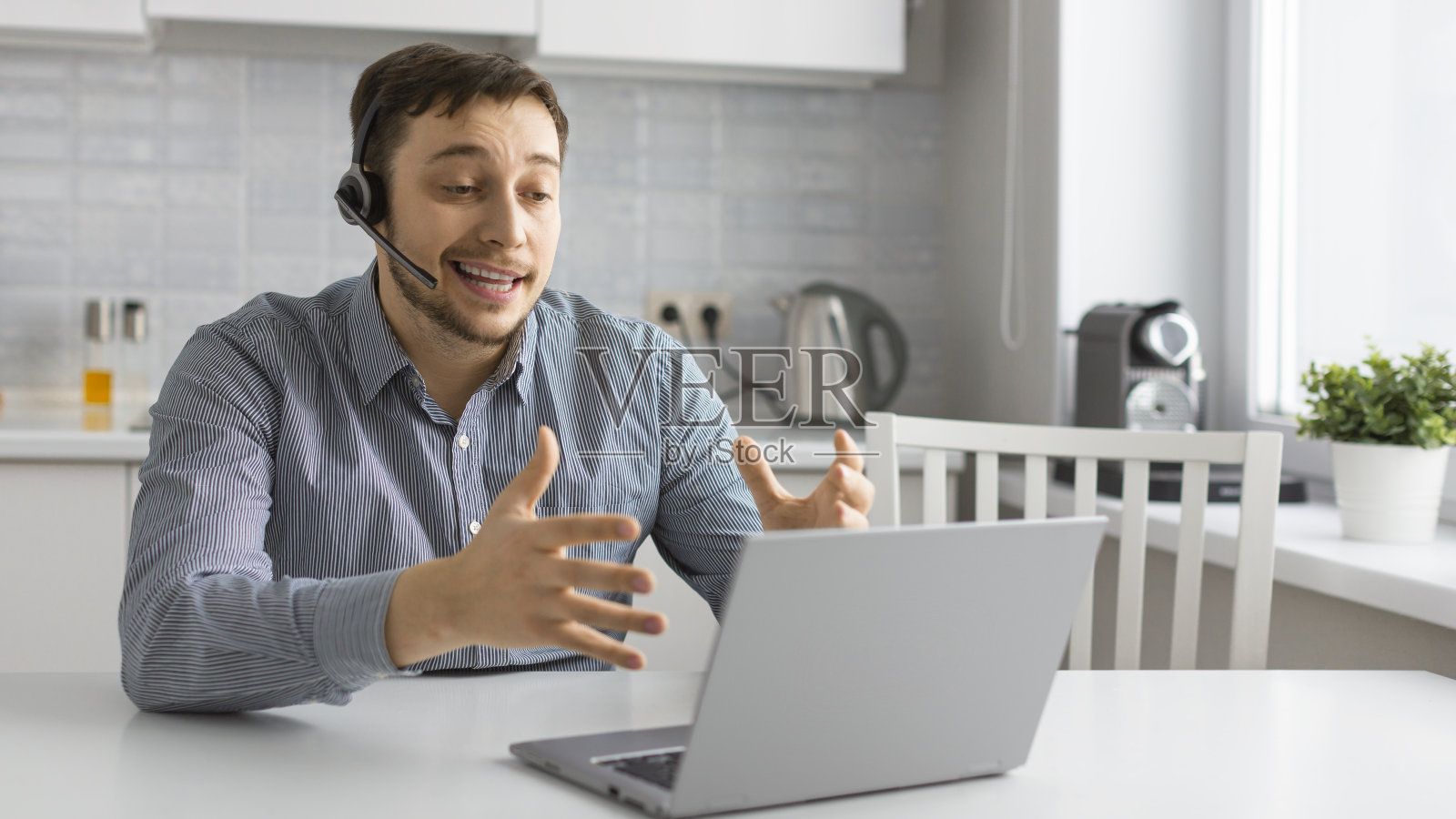 一个年轻人在手提电脑前戴着耳机进行在线视频通话照片摄影图片