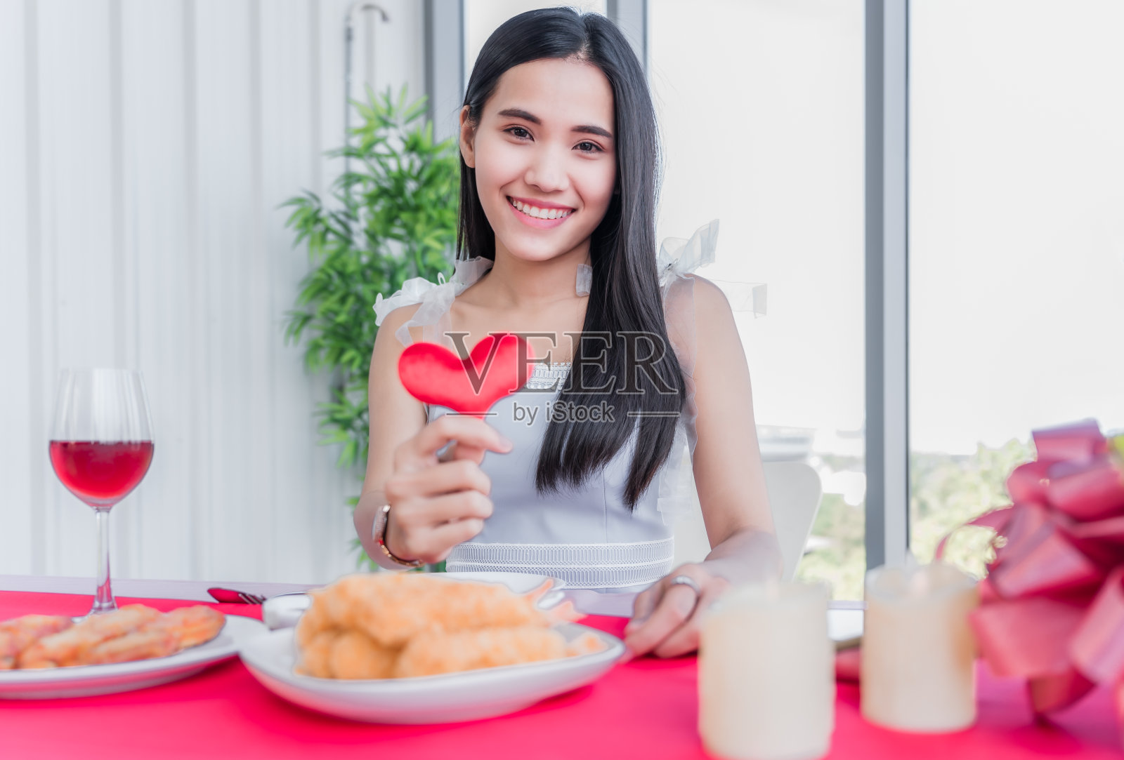美丽的亚洲年轻女子坐和快乐的微笑与显示红色心形在餐厅照片摄影图片