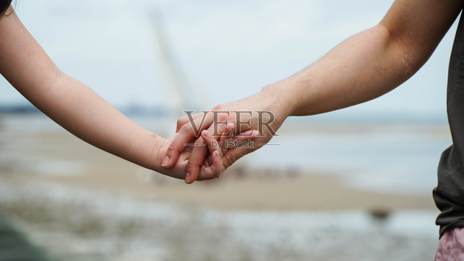 牵着女儿的手在海边散步的母亲相信家庭观念。照片摄影图片