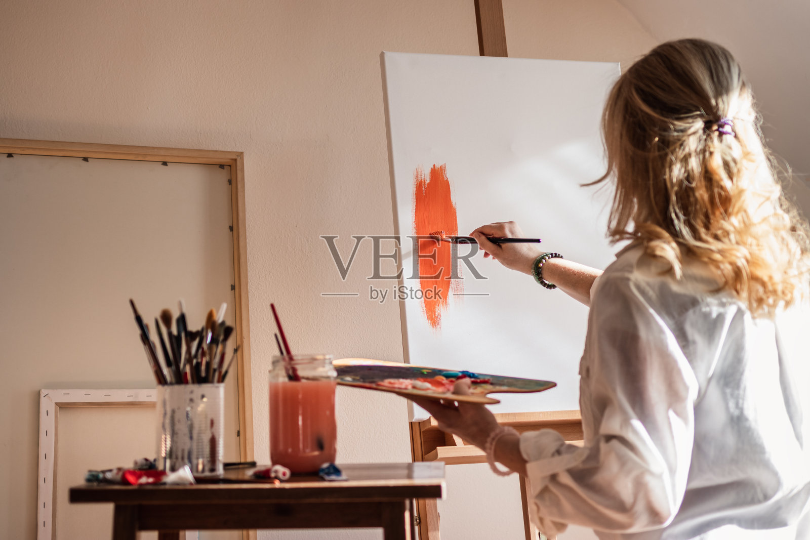 女艺术画家在她的工作室的帆布上绘画照片摄影图片