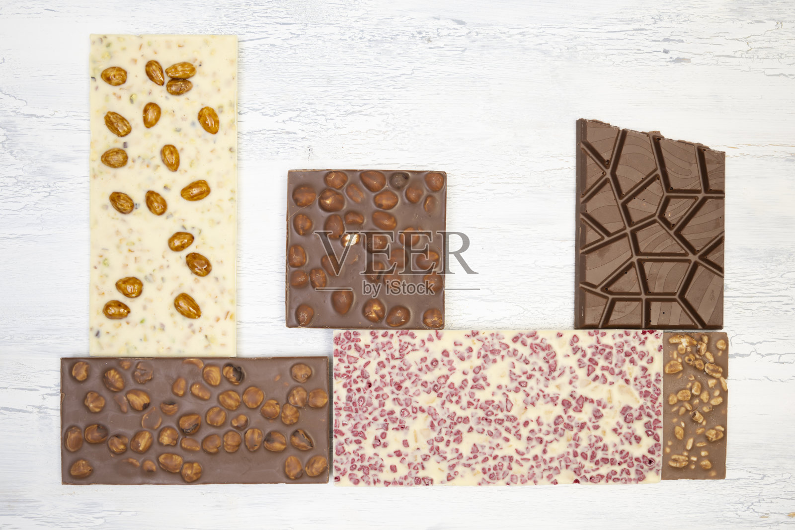 许多不同的甜蜜、精致的巧克力棒创造性地躺在白色的木质背景上照片摄影图片