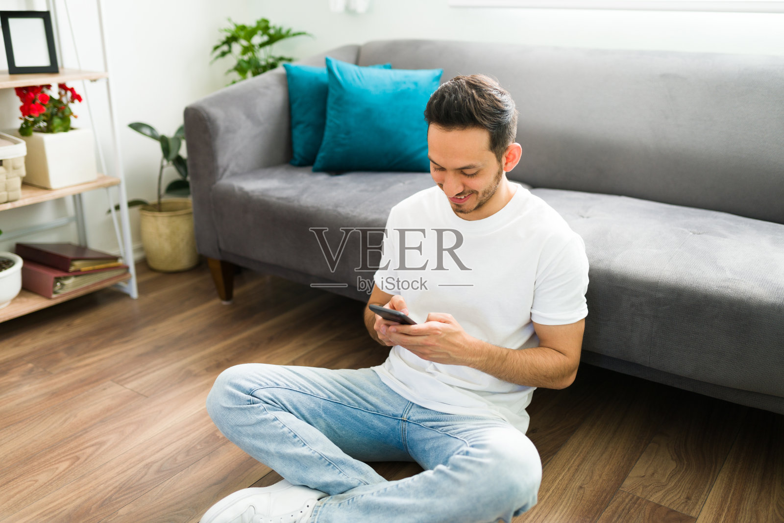 一名拉丁男子坐在客厅里，在社交媒体上发布了一张照片照片摄影图片